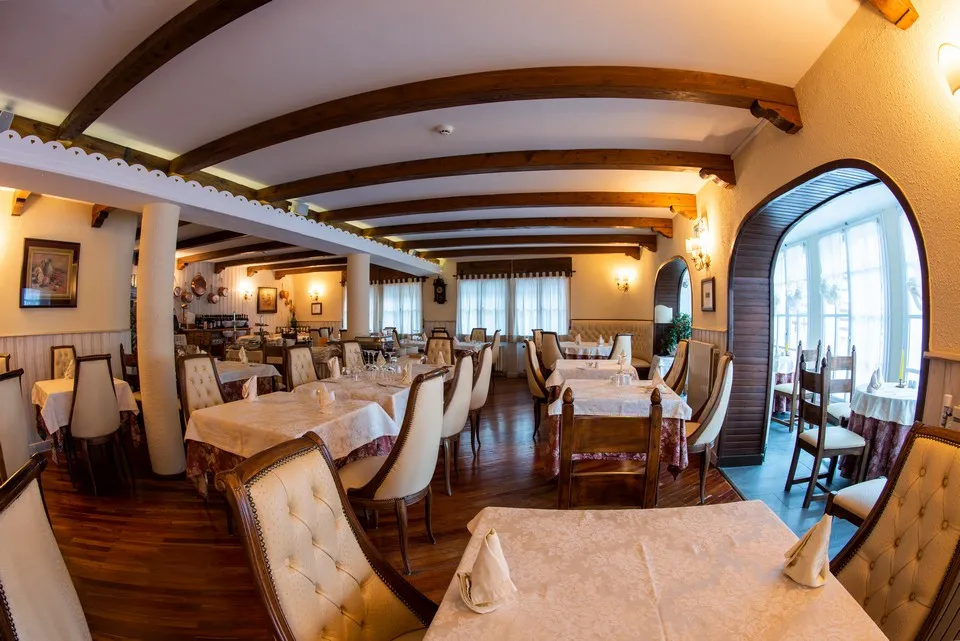 La sala del ristorante vista in profondità, con i tavoli apparecchiati e la veranda sullo sfondo